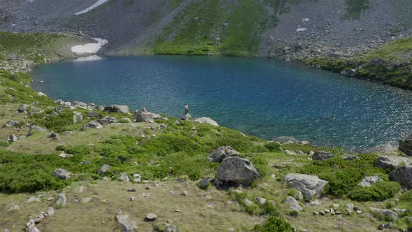 Aerial view. Alone woman traveler watching on turquoise mountain lake Arkhyz nature Caucasus Russia alt