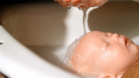 Mother giving her baby boy a bath in bathroom 4k alt