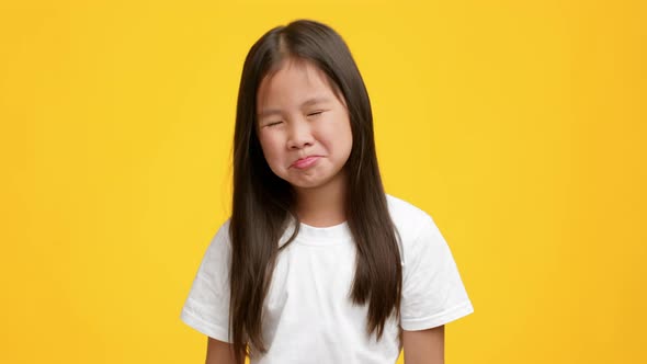 Naughty Little Japanese Girl Sulking And Grimacing Over Yellow Background alt