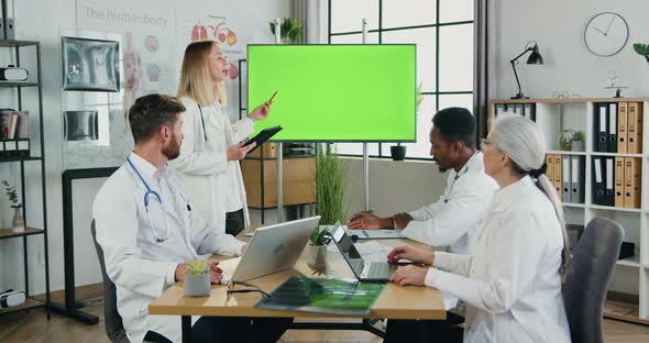 Male and Female Medical Workers Holding Joint Briefing in Medical Cabinet and Use Green Chroma Key alt