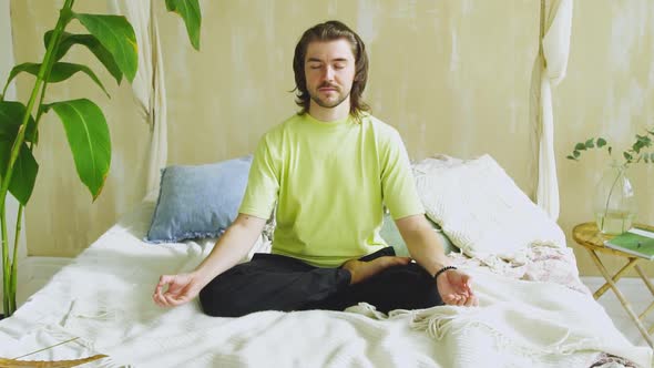 Relaxed Concetrated Man in Lotus Pose Meditating at Home alt