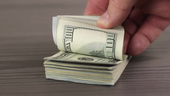 hand of man taking a pack of cash one hundred american dollar banknotes alt