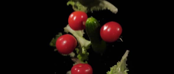 Tasty Wet Tomatoes Cucumbers and Lettuce Tossed Up and Fly Around on a Black Background in Slow alt