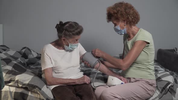 Mature Woman Wearing Face Masks Measuring Blood Pressure of Senior Elderly Female During Outbreak alt