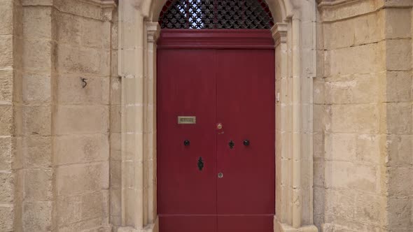 Big Closed Red Wooden Doors with Metal Bars on Top of It in Mdina