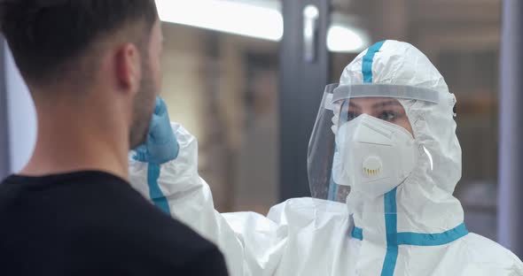 Female Doctor Wear Chemical Protection Takes a PCR Swab From a Man Test for the Presence of alt