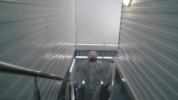 Workers in Protective Suits Walk Through the Factory