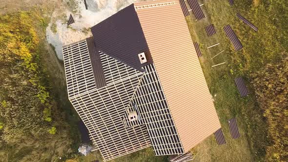 Aerial view of unfinished house with wooden roof structure covered with metal tile sheets under alt