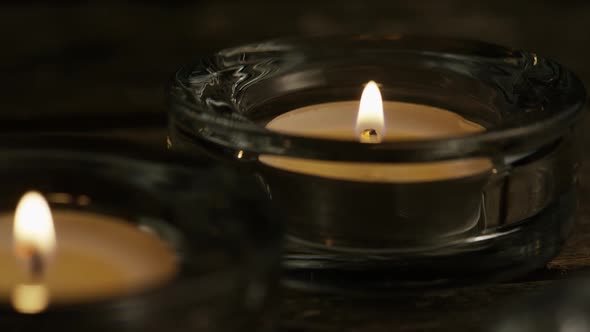 Tea candles with flaming wicks on a wooden background - CANDLES 010 alt