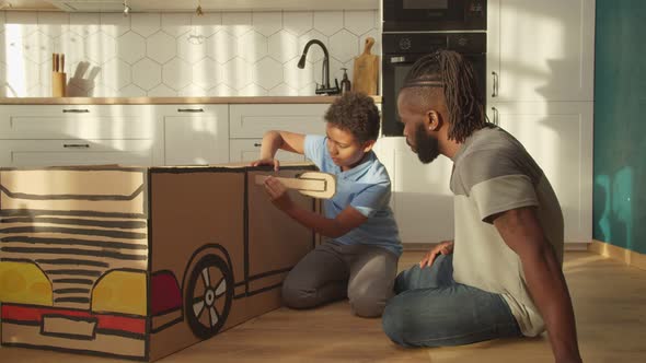 Loving African Dad and Son Creating Diy Car Toy From Cardboard at Home alt