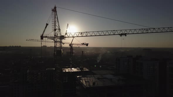 Construction Site at Sunset. Silhouette of a Construction Crane Near the Building