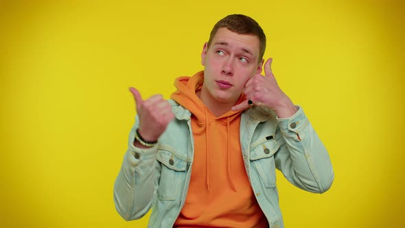 Cheerful Man in Denim Jacket Looking at Camera Doing Phone Gesture Like Says Hey you Call Me Back alt