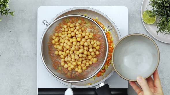 Anonymous person adding chickpea water into vegetables alt
