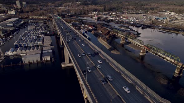 Cars driving on Ironworkers Memorial Bridge and train passing on Second Narrows rail, Vancouver in C alt