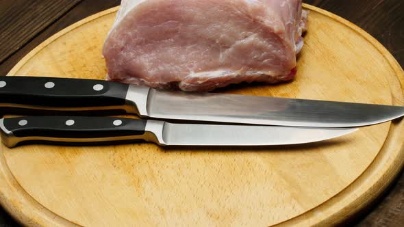 The butcher prepares meat and knives. The cook lays out piece of meat and set of sharp knives