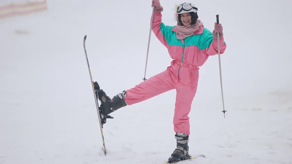 Joyful Caucasian Slim Woman Grimacing Standing on Skis Gesturing with Ski Poles alt