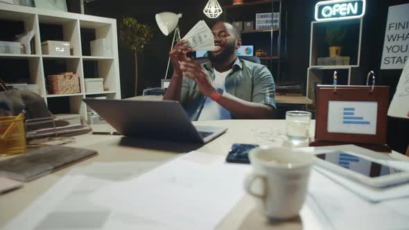 Handsome African American Business Man Enjoying Money Smell in Hipster Office. alt
