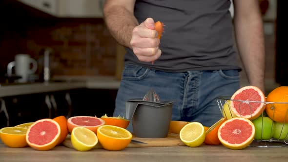 A Man is Squeezes Orange Juice with Citrus Juicer alt