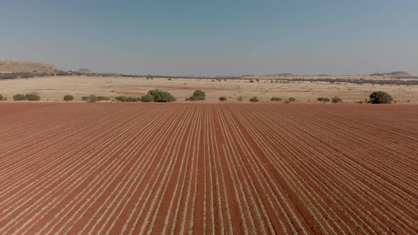 Aerial over unused plowed land crossing a gravel road alt