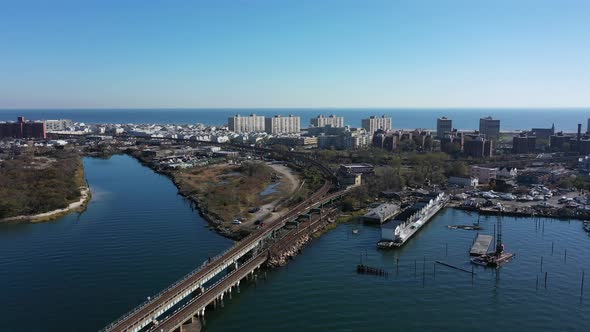 An aerial shot over Grassy Bay in Queens, NY. The camera dolly in near elevated train tracks alt