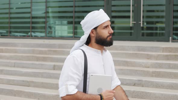 Muslim Man Walking by Office Building alt