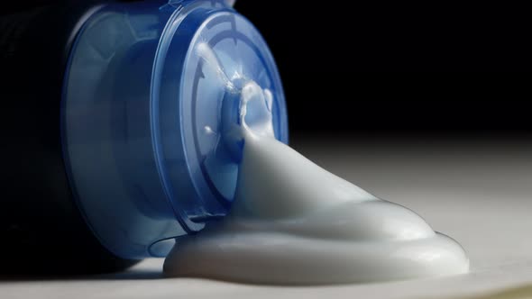 Aftershave Cream is Squeezed Out of a Tube on a Black Background alt