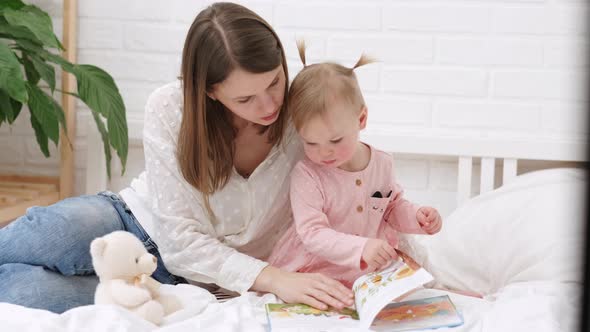 Mother and Baby Sonreading a Book in Bed Before Going to Sleep alt