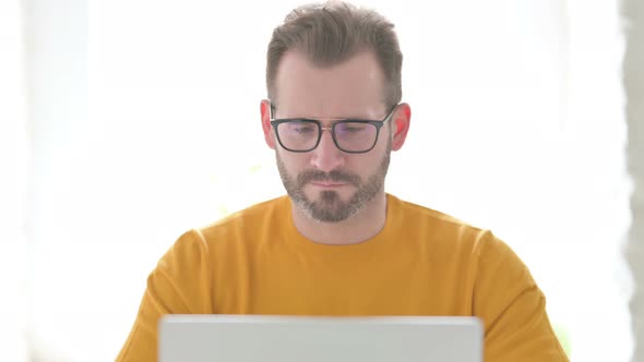 Portrait of Man with Laptop Showing Thumbs Down alt