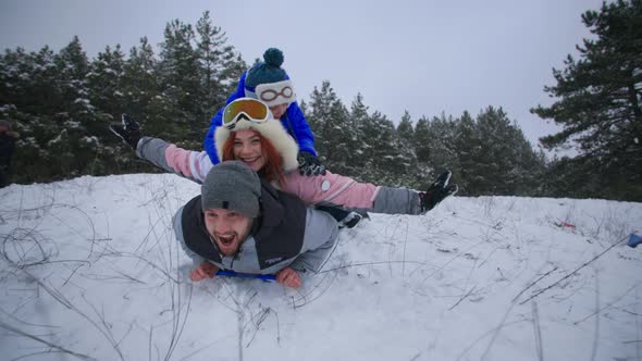 Happy Winter Joyful Active Family Have Fun Sledding Quickly Down the Snowy Slope in the Forest While