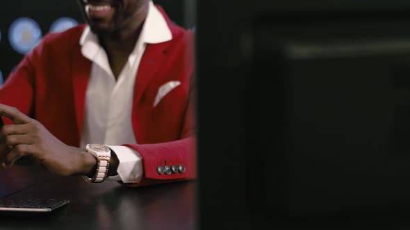 Goodlooking Black Bald Businessman in Red Suit Uses Smartphone in Dark Room