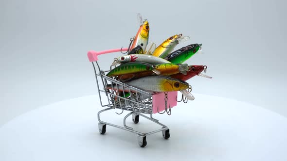 Fishing wobblers in a small shopping cart on a white background