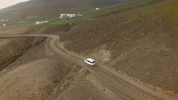 Aerial view of a family van car on a curvy and dirt road in Fuerteventura. alt