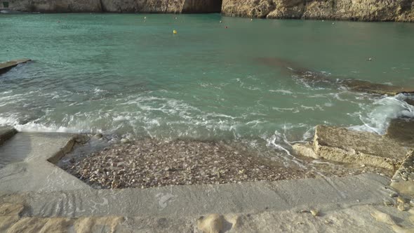 Mediterranean Sea Waves Washing Shore Filled with Pebbles near Inland Sea Caves alt