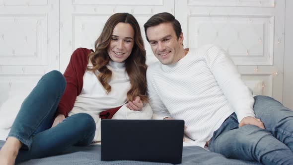 Happy Couple Watching Movie on Computer at Home Together alt