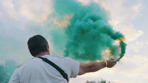 Colorful Smoke Flares Against the Sky. Slow Motion. Man Holding Smoke Bomb alt