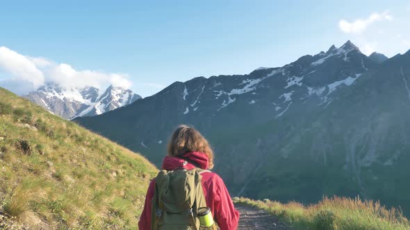 Lady Walks on Hill Slope Path Covered with Thick Grass alt