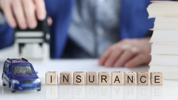 Agent Putting Seal on Document Near Wooden Cubes with Words Auto Insurance  Movie Slow Motion alt