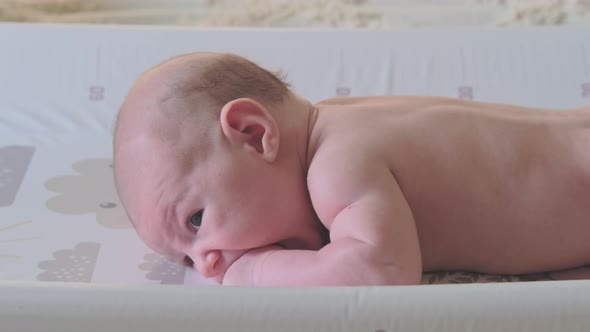 The baby lies and sucks his hand because of teething teeth