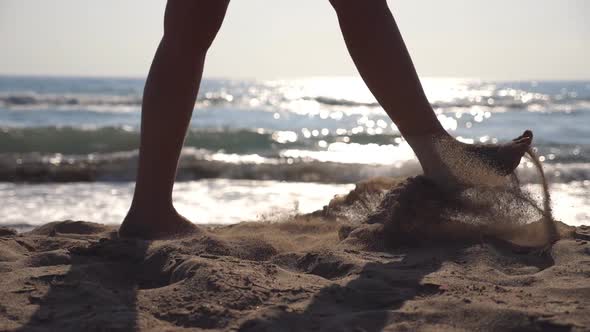 Female Feet Walking at the Sea Beach on a Sunny Day with Waves at Background alt