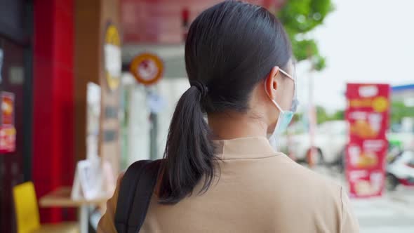 Asian woman wearing protective face mask walking at park.