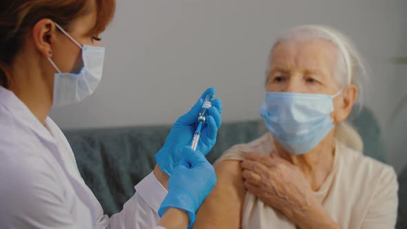 Medical Nurse Doing Injection of Coronavirus Vaccine to Senior Woman alt