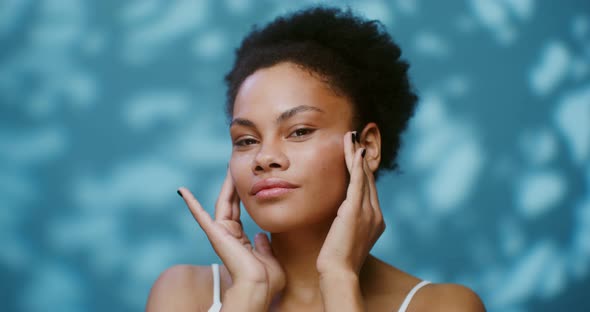 Sensual Young African American Woman Applying Moisturizer to Her Face alt