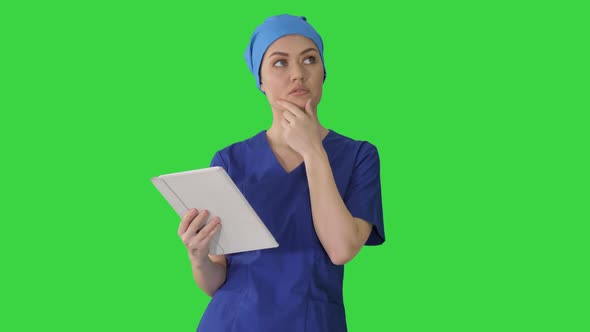 Young Woman Doctor or Nurse in Scrubs Using a Touchscreen Computer While Walking on a Green Screen alt