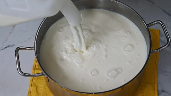 Pouring Milk Into a Metal Pot From a Gallon