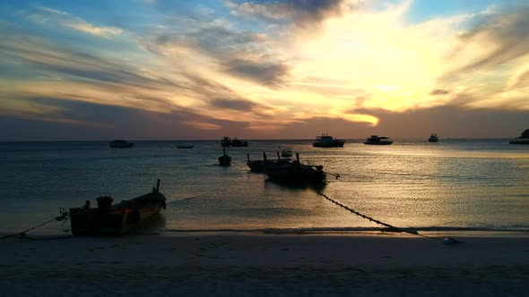 A wide shot of an ocean while the sun is setting with the boat and waves on the foreground and cloud alt