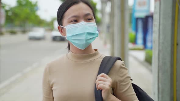 Asian woman wearing protective face mask walking at city street.