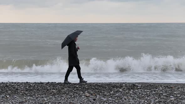 Man Walking on the Beach with Umbrella in Rain