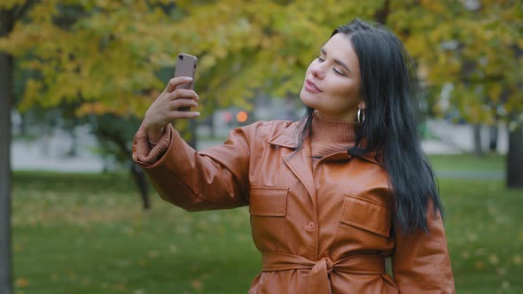 Closeup Young Hispanic Woman Stands in Autumn Park Holding Phone in Hand Girl Blogger Posing alt