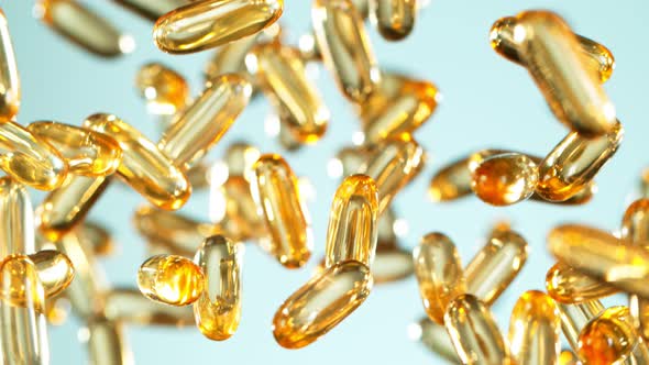 Super Slow Motion Shot of Flying Golden Capsules on Gradient Background at 1000Fps alt