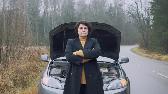 Stressed Female Driver Standing in Front of Open Hood